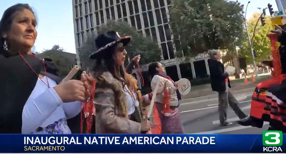 Members of Native American community in regalia and with instruments marching in the Inaugural Native American Heritage Parade in Sacramento.